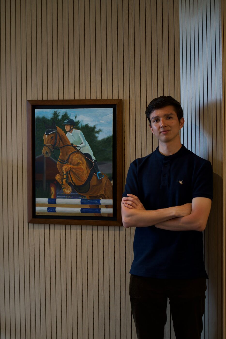 Juan Felipe Ruge standing beside one of his framed paintings